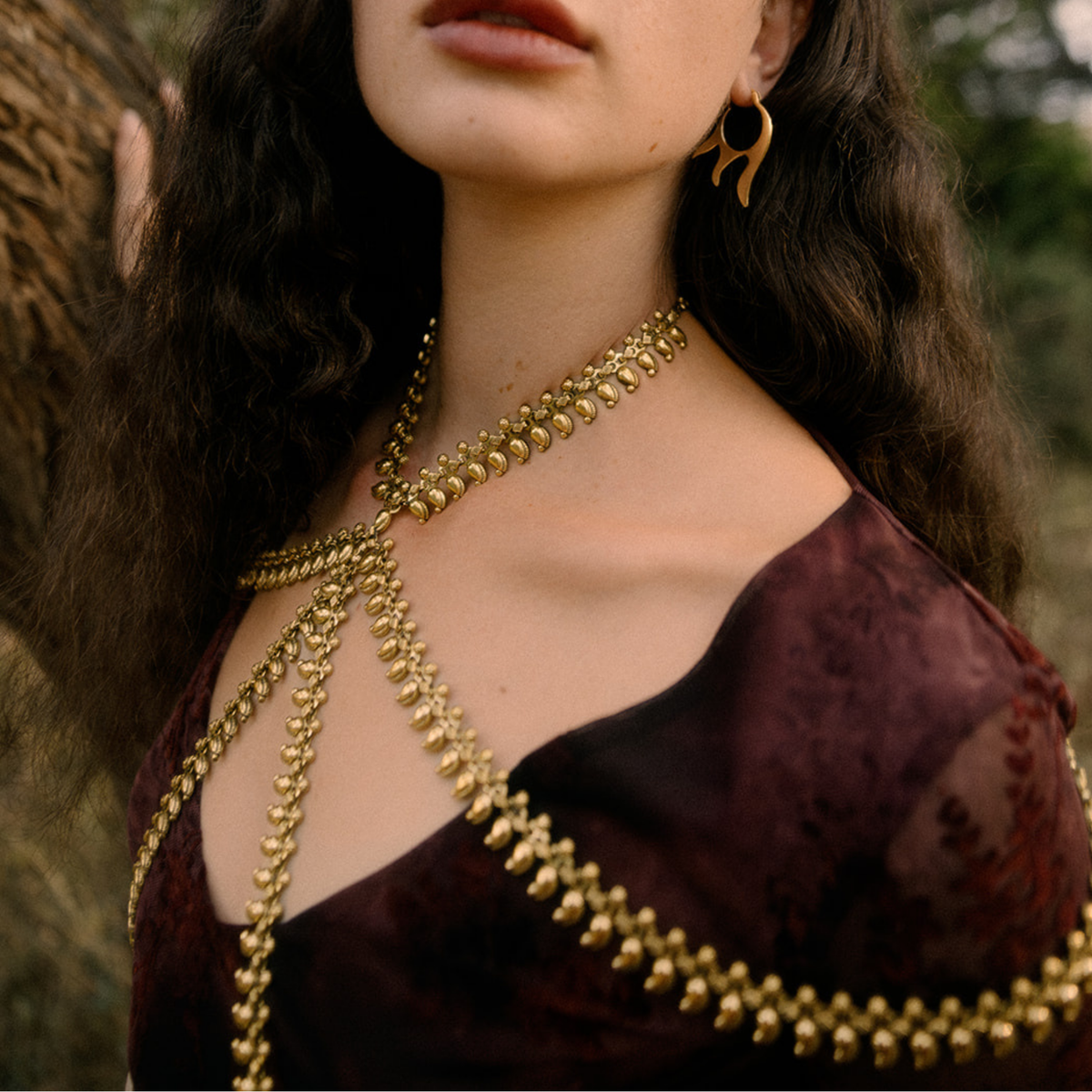 Gold beaded body chain necklace draped across the chest and shoulders 