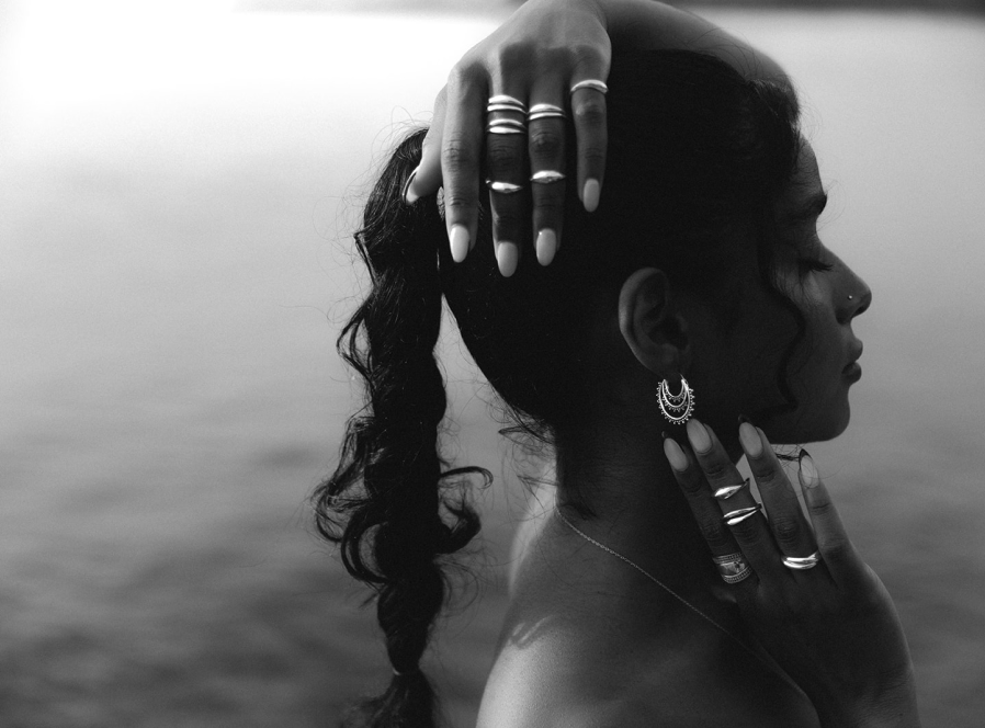 A black and white side image of a woman wearing rings and earrings.