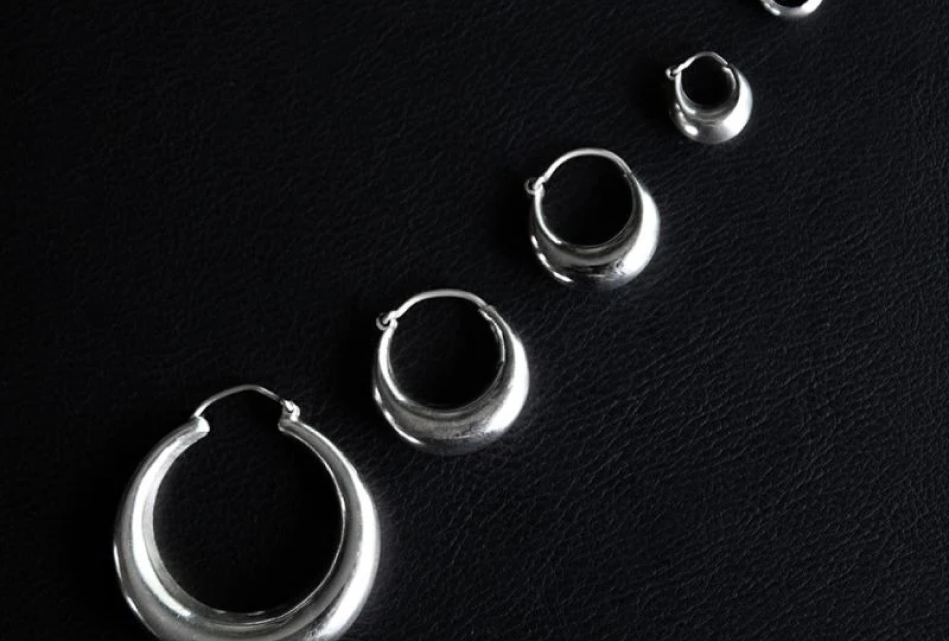 Woman wearing stacked sterling silver huggie earrings with helix studs and handcrafted silver rings by Noir KĀLA.